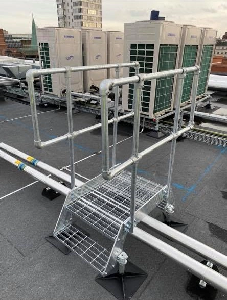Narrow mini roof stepover with galvanized handrails and stainless steel platform for pipe protection