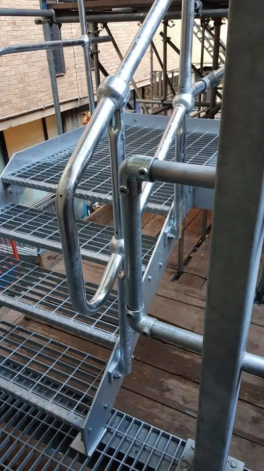 Galvanized access staircase leading from walkway with side rails and anti-slip finish